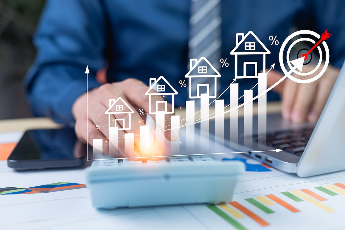 Real estate investor using a calculator at a desk with a laptop, smartphone, and financial charts, overlaid with a graphic showing rising bar chart with house icons and percentage symbols representing increasing property values and investment growth