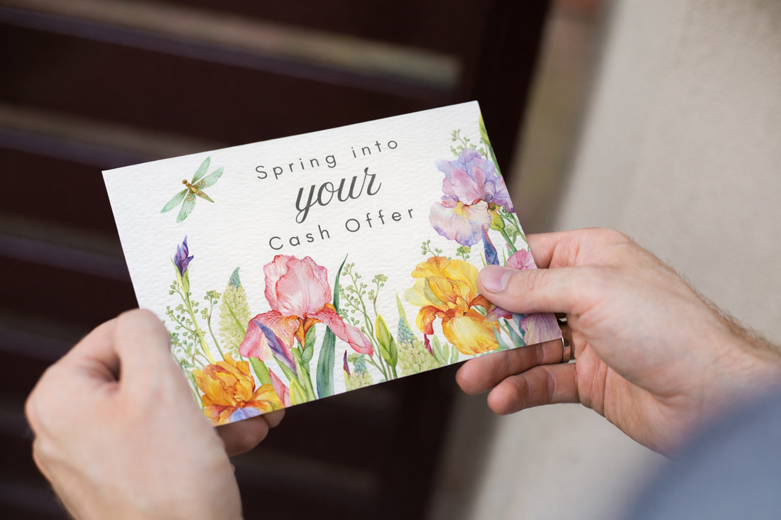 A person holds a postcard featuring watercolor florals with two hands