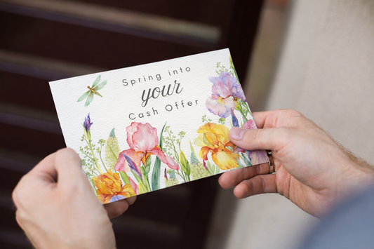 A person holds a postcard featuring watercolor florals with two hands